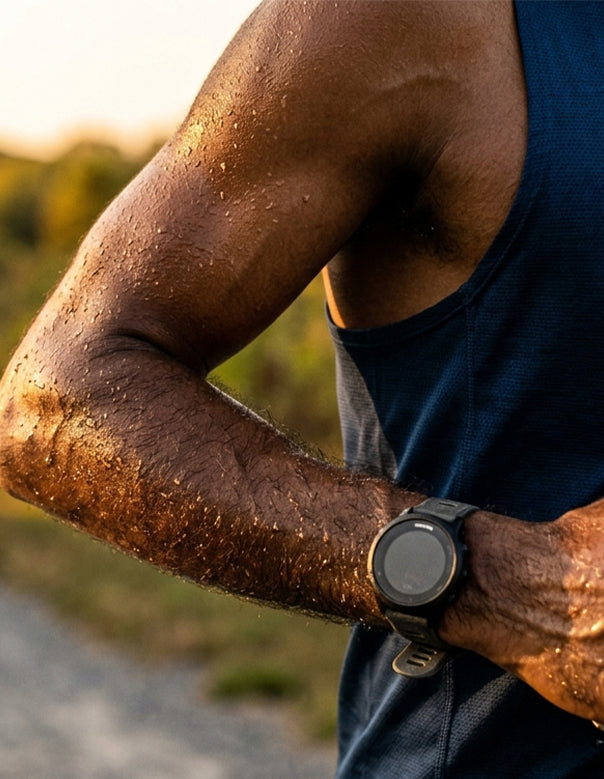 Close-up of a runner's arm with sweat droplets mid-run — illustrating electrolyte loss through sweat