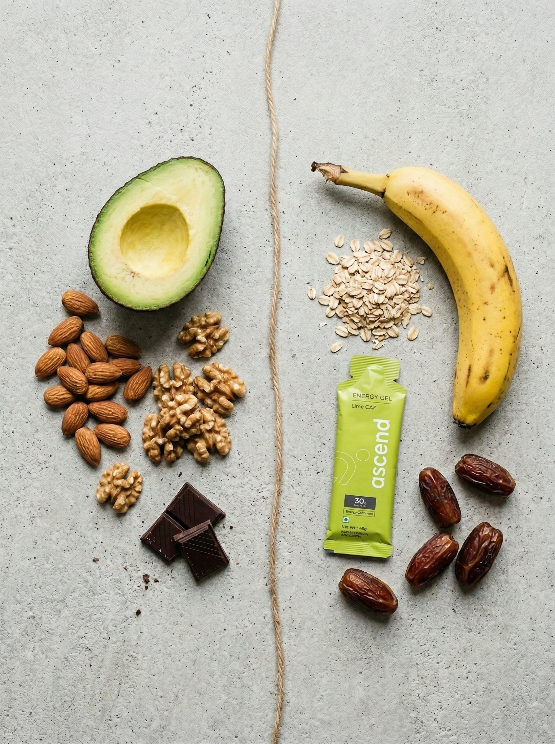 Flat lay of fat sources and carbohydrate sources side by side — nuts, avocado and dark chocolate on one side, banana, oats, dates and an energy gel on the other — illustrating the two primary fuel systems the body uses during endurance activity